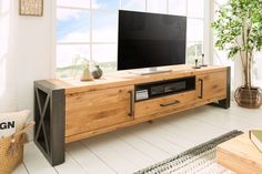 a flat screen tv sitting on top of a wooden entertainment center next to a window