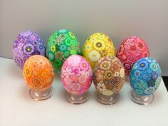 there are many different colored decorated eggs on the table together in this row, all lined up and ready to be painted