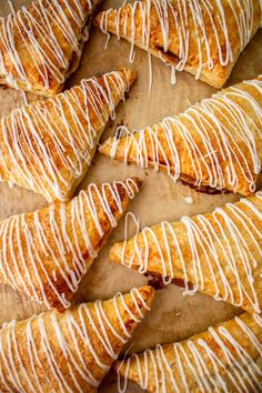 several croissants with white icing on them sitting on a piece of parchment paper