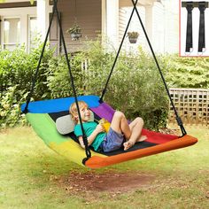 a young boy sitting in a rainbow colored hammock swing with his toddler