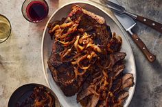 steak with onions on a plate next to wine glasses and utensils