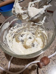 a glass bowl filled with cream and chocolate chip cookie dough on top of a counter