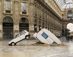 an upside down car is in the middle of a building with a broken window and roof