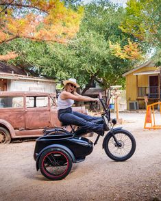 a woman riding on the back of an old fashioned motorcycle