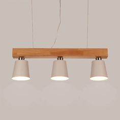 three lights hanging from a wooden beam with white shades on them and one light in the middle