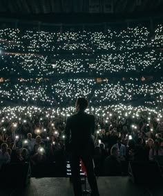 a man standing in front of a large crowd holding up cell phones with lights on them