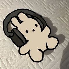 a white teddy bear sitting on top of a bed with headphones around its neck