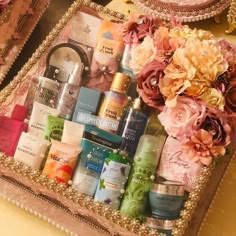 an assortment of beauty products and flowers in a tray on a table with gold sequins