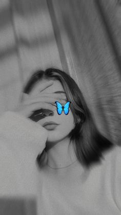 a woman covering her eyes with a blue butterfly on her forehead in black and white