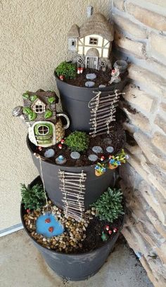 there is a tower made out of pots with plants and houses in them on top