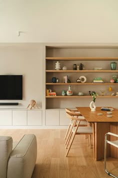 a living room filled with furniture and a flat screen tv mounted on a wall above a wooden dining table