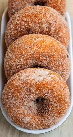 several sugared donuts in a white dish on a table