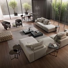 a living room filled with lots of furniture next to a large glass wall covered in windows