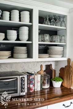 a kitchen with white cupboards filled with dishes and utensils on top of a wooden counter