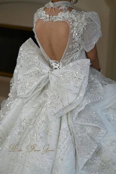 the back of a white wedding dress with a large bow on it's neck