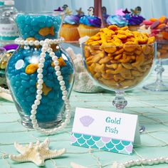 a table topped with glass vases filled with candy next to other decorations and seashells