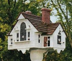 a white bird house in the middle of some trees