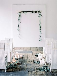 a room with white chairs and candles on the floor