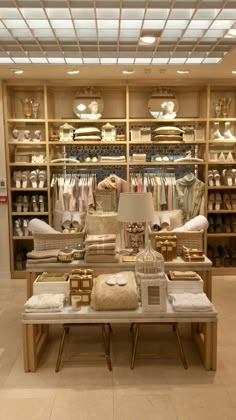 the inside of a clothing store with lots of items on tables and lamps hanging from the ceiling