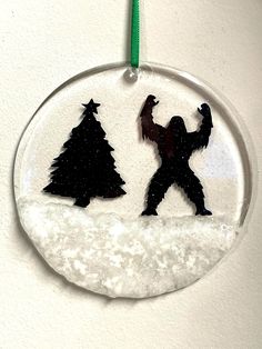 a glass ornament with a silhouette of a gorilla and trees in the snow