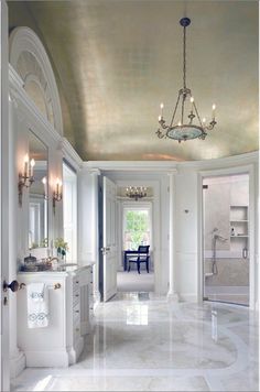 an elegant bathroom with marble floors and chandelier hanging from the ceiling above it