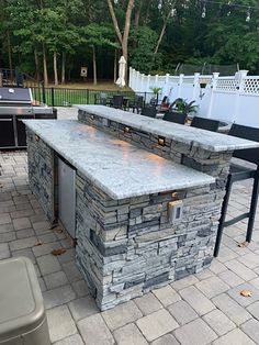 an outdoor kitchen with stone counter tops and grilling area in the back yard,