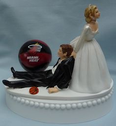 a wedding cake topper with a basketball and bride on it's lap next to the groom