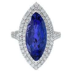 This opulent ring is a true showstopper, crafted with 18KT white gold and featuring a resplendent 6.81CT marquise-cut tanzanite. The tanzanite is complemented by a dazzling array of 1.25CT-TW F-G color and VS/I clarity round-cut diamonds, ensuring a stunning display of sparkle and shine. This exquisite combination of precious gemstones and diamonds makes for a luxurious and eye-catching statement piece. GAL Certified. Size 6 US. Weight 7.7 gm. Tanzanite And Diamond Ring, Tanzanite Diamond Ring, Tanzanite Diamond, Tanzanite Ring, Precious Gemstones, Round Cut Diamond, Birthstone Jewelry, Cocktail Rings, Tanzania