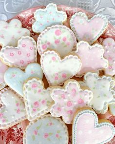 decorated cookies in the shape of hearts on a pink and white plate with red flowers