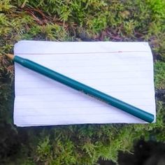 a notepad with a pencil resting on top of it next to some green plants