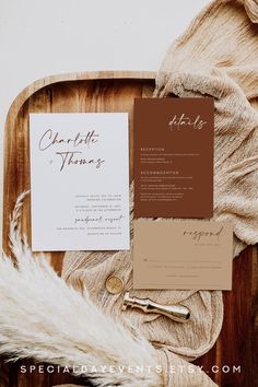 the wedding stationery is laid out on a wooden tray