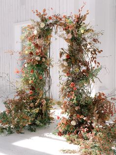 two archways covered in flowers and greenery next to a white building with an open door