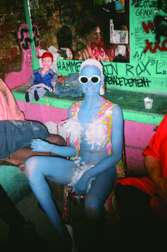 a man with blue paint on his body sitting in front of a counter