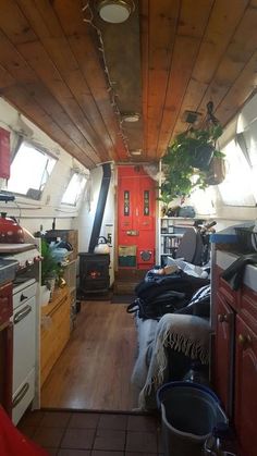 the inside of a small home with wood floors and red doors, windows, and lots of clutter