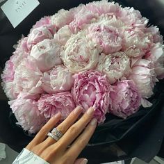 a woman's hand holding a bouquet of pink and white peonies