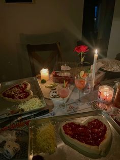 a table topped with lots of food next to candles and plates filled with food on top of it