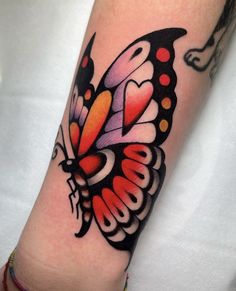 a colorful butterfly tattoo on the arm with dots and hearts in it's wings