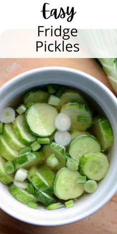 a white bowl filled with sliced cucumbers on top of a wooden table