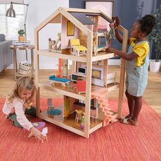 two children playing with a doll house on the floor