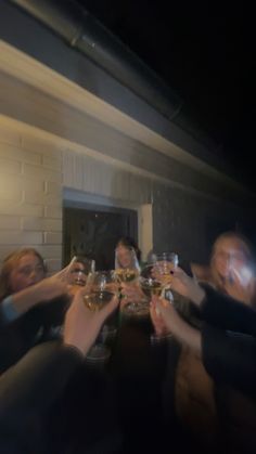 a group of people toasting with wine glasses in front of their faces at night