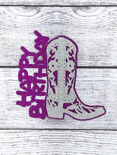 a cowboy boot with the word happy birthday in purple and silver glitter on white wood