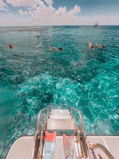 people swimming in the ocean on a boat with clear water and blue skies above them