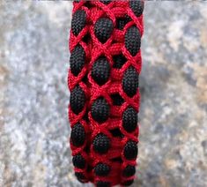 a red and black crochet bracelet on a rock