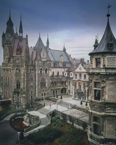 an old castle like building with steeples on the roof and stairs leading up to it