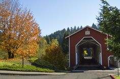 a red covered bridge with trees in the background