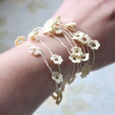 a woman's arm with four bracelets on top of it and flowers in the middle