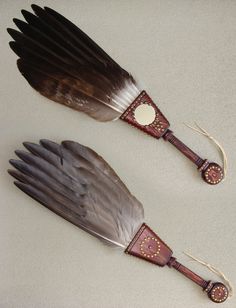 two brown and white feathers on top of each other next to a pair of scissors