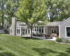 a house with a large lawn in front of it and trees around the back yard