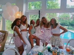 a group of women standing next to each other in front of a table filled with food and drinks