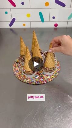 an ice cream cone with sprinkles is being held up by someone's hand